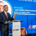 Ponente en un atril ante una pantalla de la ceremonia de apertura de la XI Semana de la Energía.