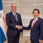 Dos personas se estrechan la mano entre las banderas dominicana y de Naciones Unidas.