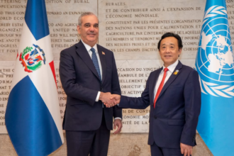Dos personas se estrechan la mano entre las banderas dominicana y de Naciones Unidas.